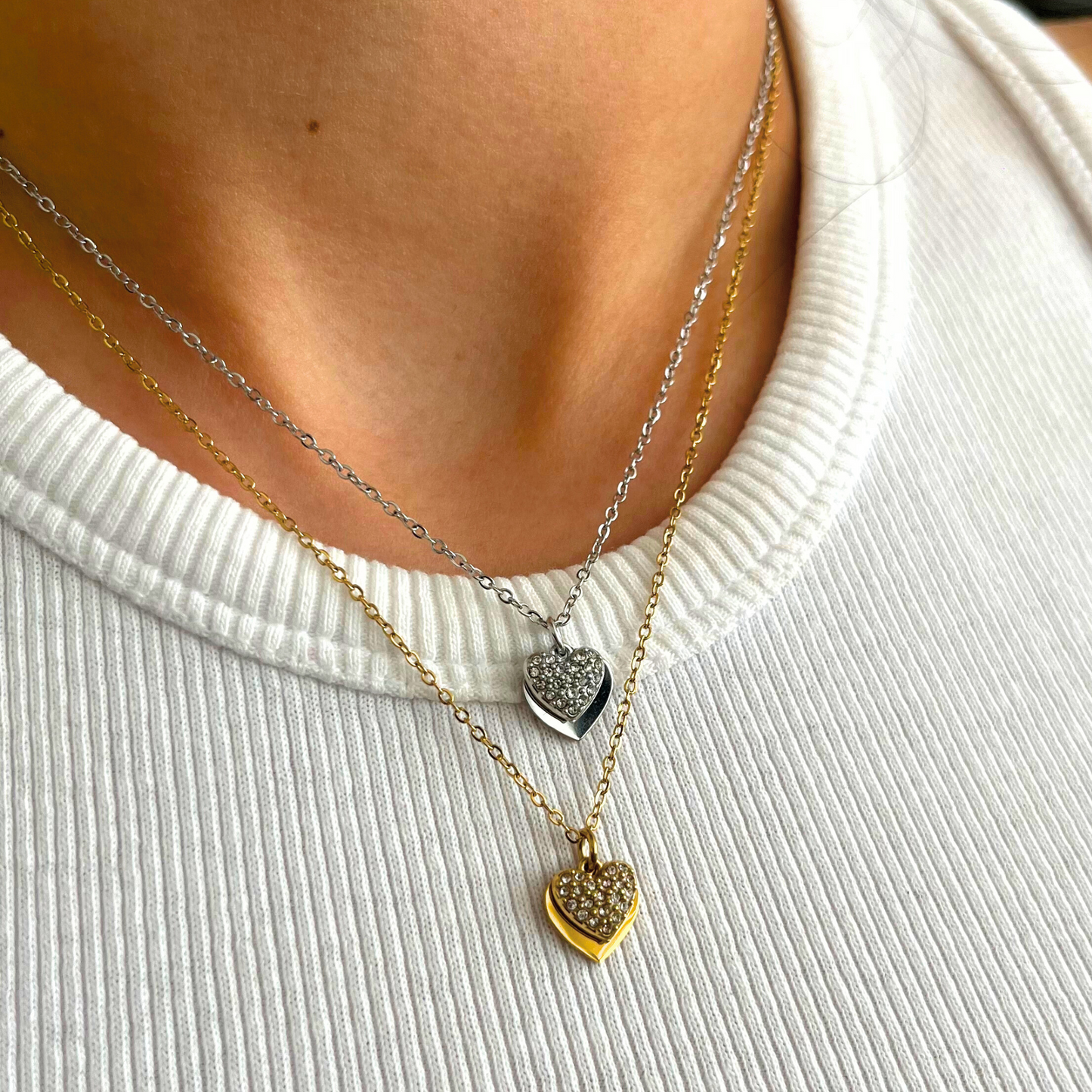Collar de acero inoxidable con doble dije de corazón: uno liso y otro con incrustaciones de circonias brillantes. Disponible en dorado y plateado.