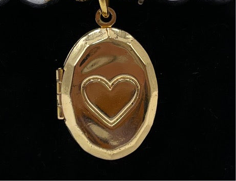 Brazalete elástico con perlas metálicas plateadas y relicario dorado en forma de óvalo, abierto y cerrado. Diseño emocional de bisutería fina.”
