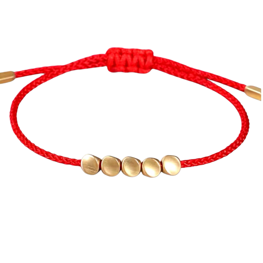 Pulsera ajustable con hilo rojo trenzado y cuencas metálicas doradas, ideal como amuleto de protección.