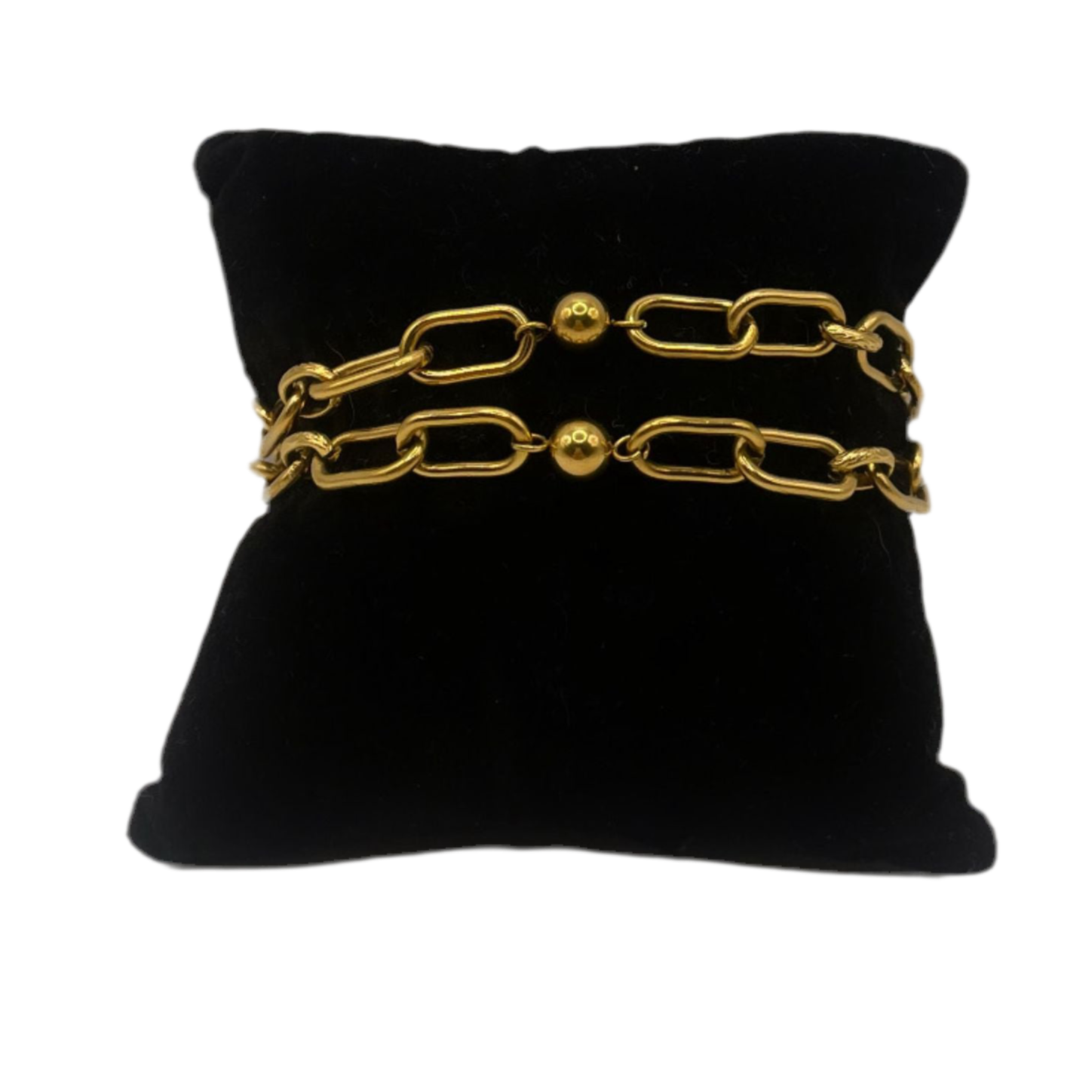 “Pulsera dorada de eslabones con esferas decorativas, exhibida sobre cojín negro. Diseño elegante